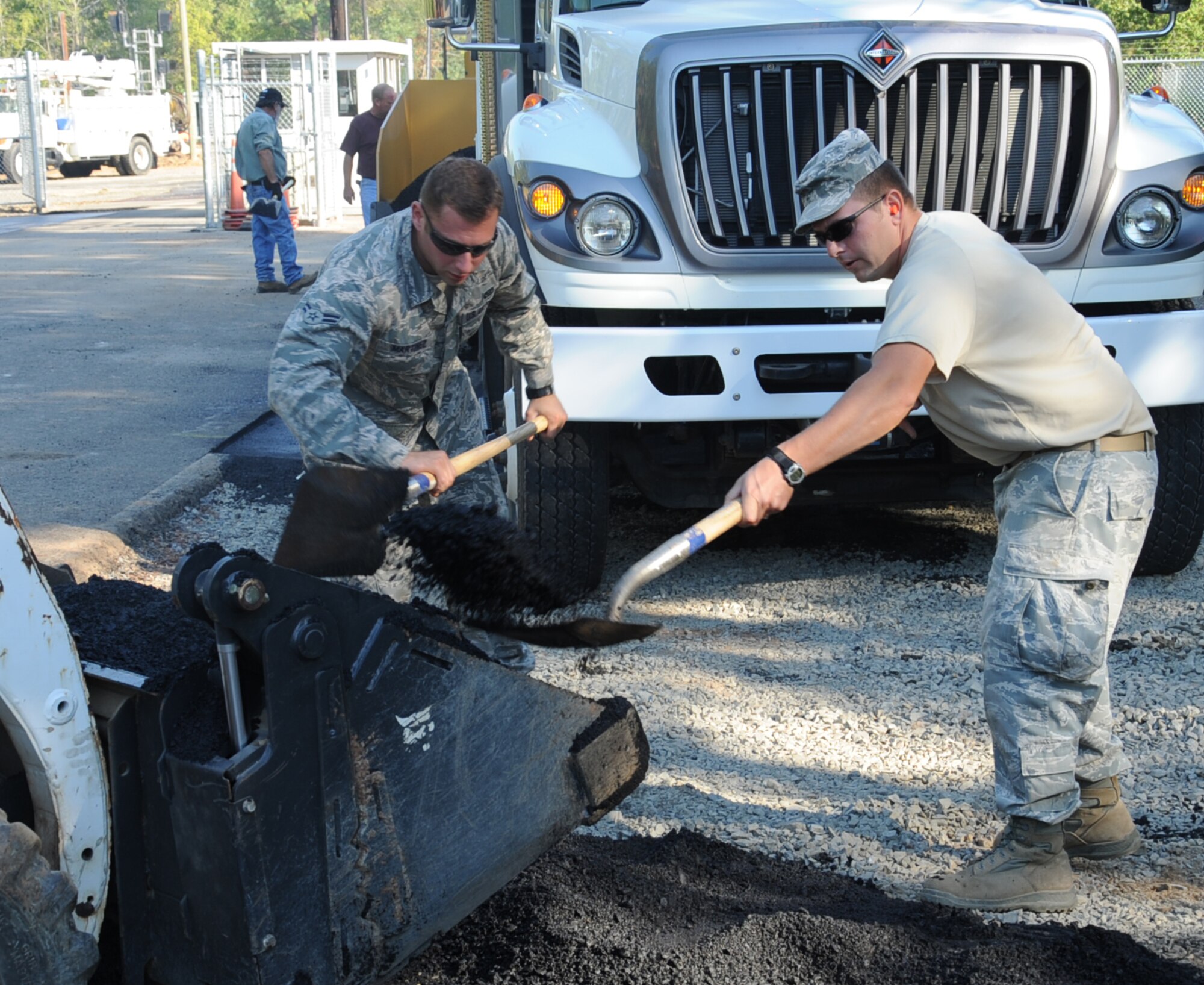 Airman 1st Class Jon Martinez, (left), and Tech. Sgt. Floyd Butkiewicz, 2nd Civil Engineer Squadron paving and equipment shop, fill a front end loader with asphalt during construction at the Bodcau gate on Barksdale Air Force Base, La., Sept. 27, 2013. CE Airmen have the responsibility of maintaining and setting up Barksdale's infrastructure, ranging from roads and pavement, construction projects and Barksdale's flightline. (U.S. Air Force photo/Senior Airman Sean Martin)
