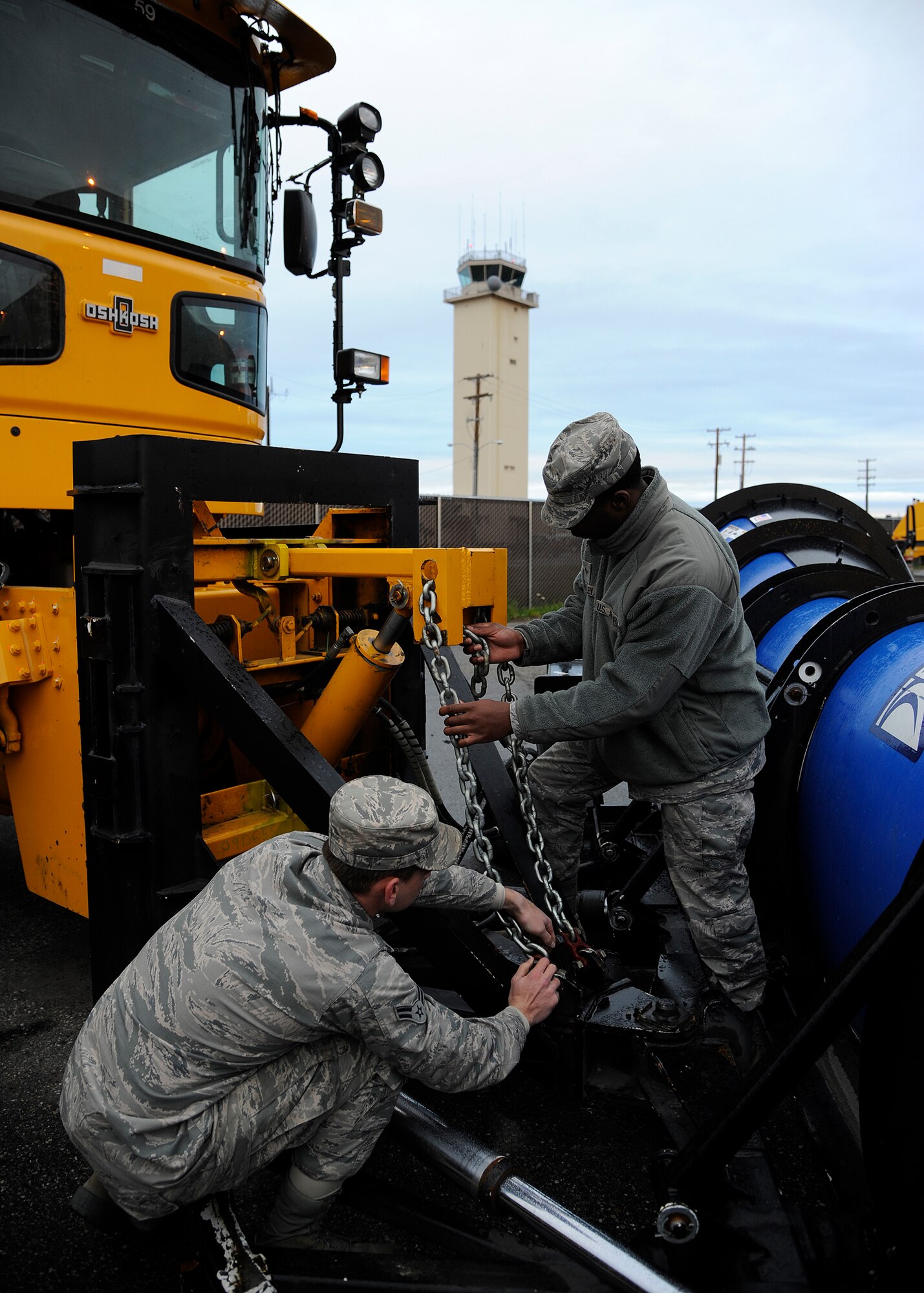 Airmen 1st Class David Cline and Trai Mobley, 354th Civil Engineer Squadron heavy equipment operators, adjust the chains on a snow plow Sept. 26, 2013, Eielson Air Force Base, Alaska. Each operator performs a preventive maintenance check before driving to ensure it is working properly. (U.S. Air Force photo by Senior Airman Ashley Nicole Taylor/Released)