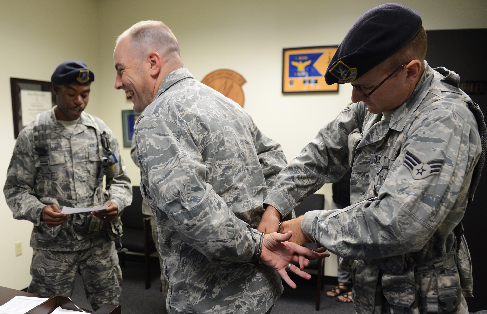 U.S. Air Force Tech. Sgt. Dontrey Lampkin, 20th Security Forces Squadron investigations, and Senior Airman Paul Nadler, 20th SFS plans and programs, place handcuffs on Maj. Christopher Sheffield, 20th SFS commander, during a SFS Jail and Bail fundraiser, Shaw Air Force Base, S.C., Sept. 26, 2013. 20th SFS held a base wide Jail and Bail fundraiser for the Defender's Association, during which they handcuffed 57 Airmen and Soldiers and raised $1,464. (U.S. Air Force photo by Senior Airman Tabatha Zarrella/Released)