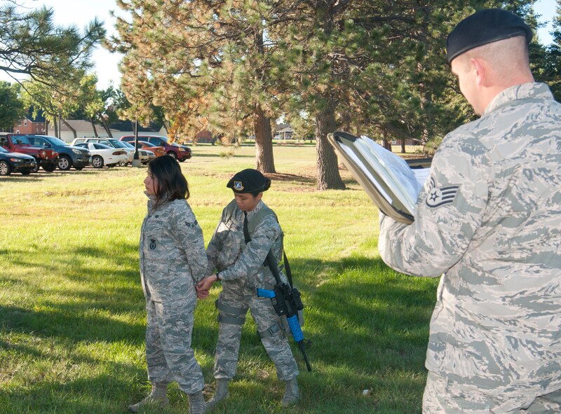 Staff Sgt. Bryan Powell, 90th Security Forces Group Standards and Evaluations, evaluates Airman Angela Lee, 790th Missile Security Forces Squadron, as she demonstrates searching and handcuffing techniques with the assistance of Airman 1st Class Tatyana Rodriguez-Gonzalez, 790th MSFS, outside Bldg. 34 Oct. 1, 2013. (U.S. Air Force photo by Airman 1st Class Jason Wiese)