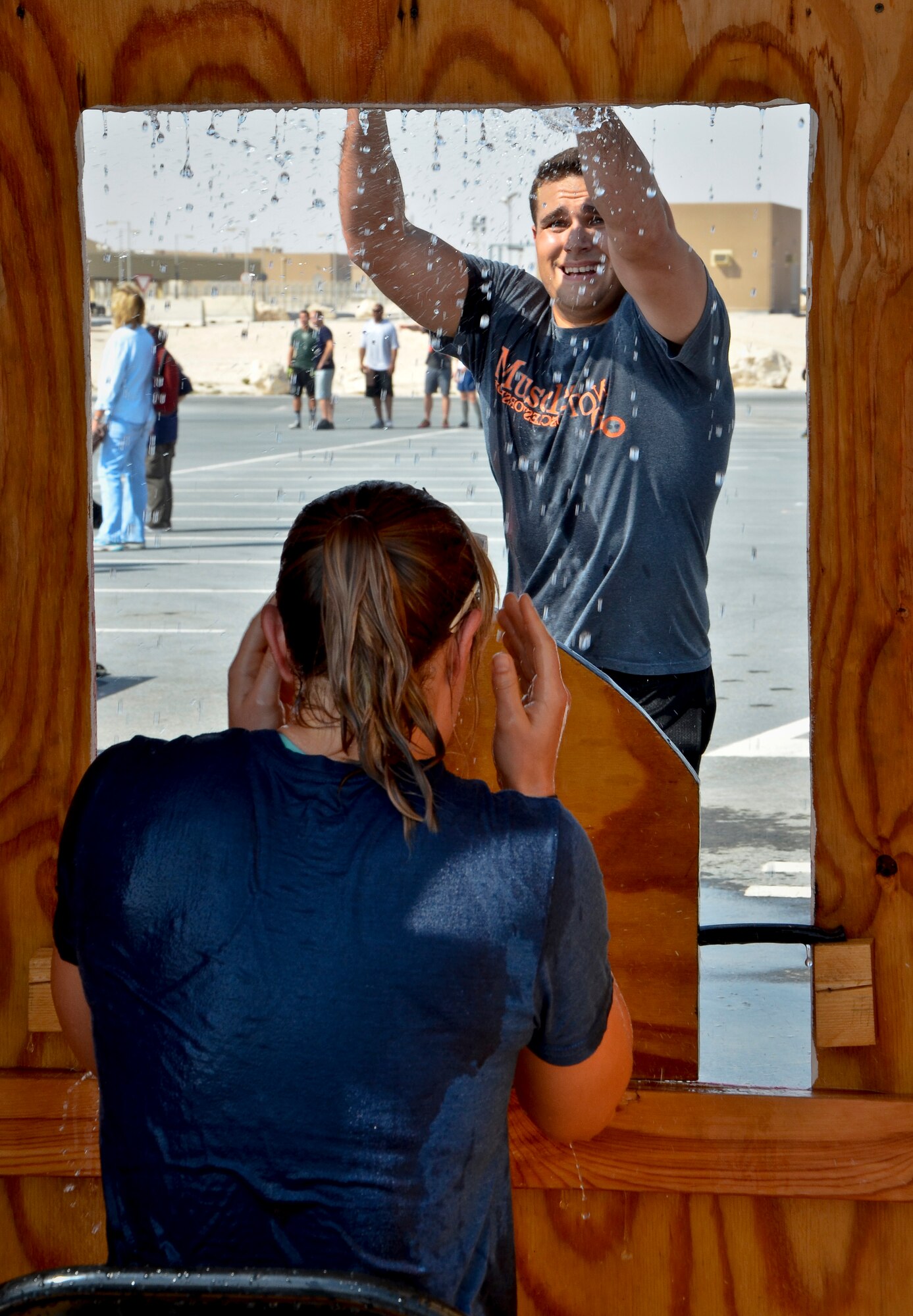 1st Lt. J.P. Henrard dowses 1st Lt. Susan Harrington “trapped by fire” during a fire muster event at the 379th Air Expeditionary Wing in Southwest Asia, Sept. 28, 2013. Henrard is a 557th Expeditionary RED HORSE Squadron project engineer deployed from Holloman Air Force Base, N.M., and hails from St. Petersburg, Fla. Harrington is the 379th AEW public affairs flight chief deployed from Davis-Monthan Air Force Base, Ariz., and a Frankfort, Ky., native. (U.S. Air Force photo/Staff Sgt. Benjamin W. Stratton)