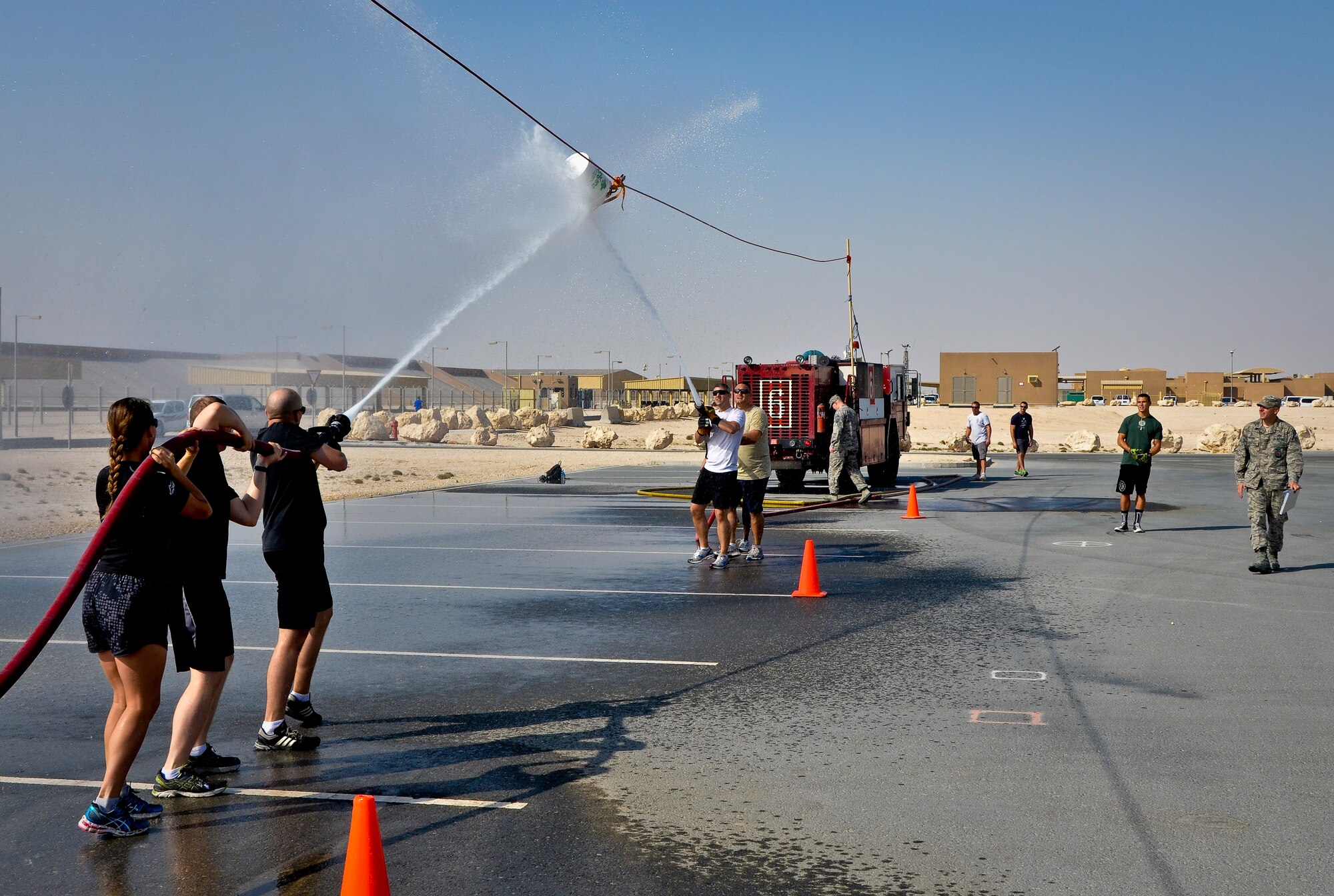Service members participate in a fire muster event at the 379th Air Expeditionary Wing in Southwest Asia, Sept. 28, 2013. Teams had to get the bucket past their opponent’s cone by blasting the bucket with water during this event. More than 80 service members in 20 teams pitted their might in a firefighting flavored challenge wrestling everything from hoses and tires to water buckets and fire trucks. (U.S. Air Force photo/Staff Sgt. Benjamin W. Stratton)