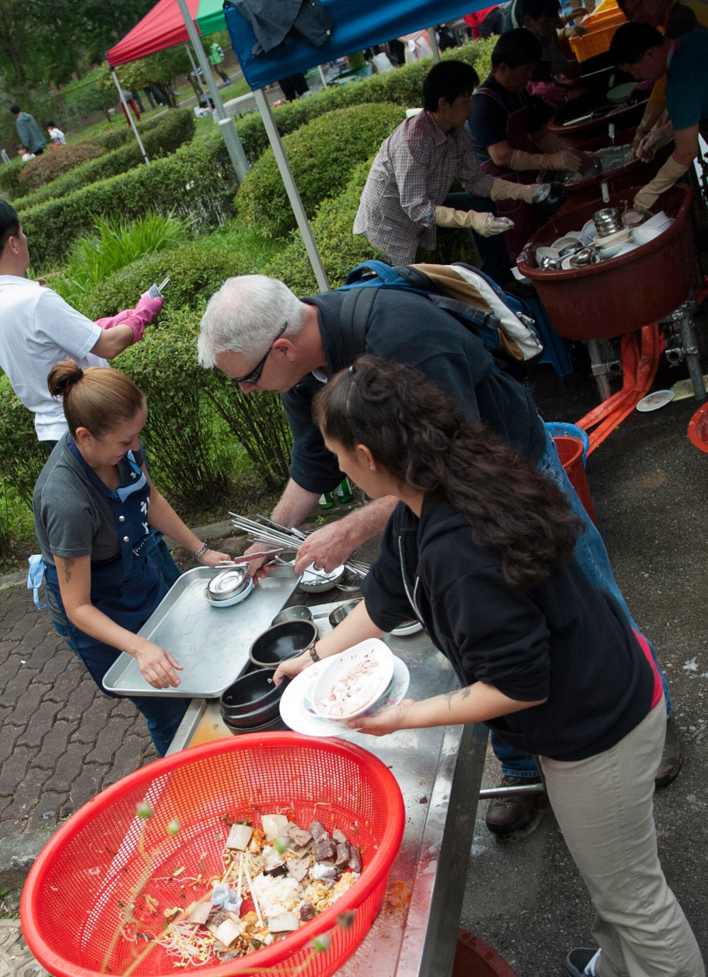 Master Sgt. Rosie Lopez, 8th Medical Group, left, Chaplian (Lt. Col.) Bryan Hochhalter, 8th FW, top right, wash dishes at the  Mount Saint Joseph Home for the Aged family day in Haewol-ri, Republic of Korea, Sept. 28, 2013. Wolf Pack Airmen volunteered at the event to work and visit with local families. (U.S.  Air Force photo by Tech. Sgt. Alex Griffin/Released)