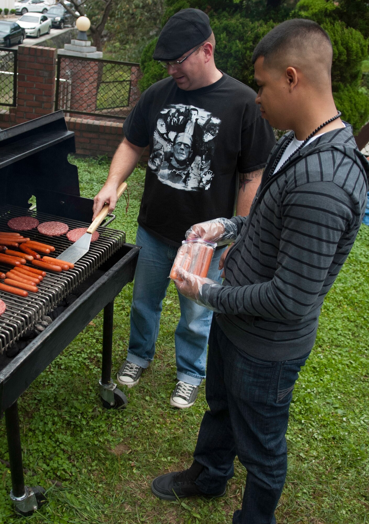Technical Sgt. Benjamin Benadum, 8th Maintenance Group, left, and Senior Airman Roger Espinoza, 8th Maintenance Group, right, prepare hamburgers and hot dogs at the Mount Saint Joseph Home for the Aged Family Day in Haewol-ri, Republic of Korea, Sept. 28, 2013. The volunteers helped prepare meals for more than 500 visitors and raised money for the Home for the Aged.  (U.S. Air Force photo by Tech. Sgt. Alex Griffin/Released)