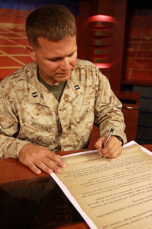 Capt. Jacob E. Hoskins, provost marshal for MCAS Iwakuni signs the Crime Prevention Proclamation at the Armed Forces Network studios here after reading it aloud for the afternoon broadcast, Oct. 1, 2013.