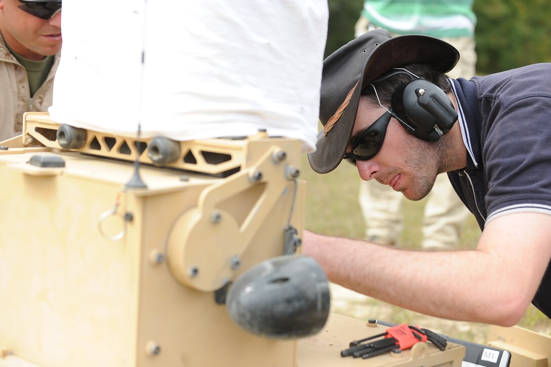Matt Cork, 24, field technician, Marathon Targets, Sydney, Australia,  repairs a T-40 robot that broke down during a live-fire exercise at Range 12 aboard Marine Corps Base Quantico on Sept. 20, 2013.  The robots have three modes operators can choose from when firing.