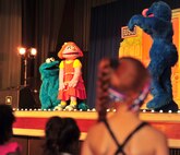 Cookie Monster and Grover discuss with Katie the opportunities that come along with moving on the The Sesame Stree/USO Experience for Military Families on Kadena Air Base, Japan, Oct. 1, 2013. Introduced in April 2011, Katies is a military child character designed to help military families cope with issues that children face when transferring to a new base. (U.S. Air Force Base by Staff Sgt. Rachelle Coleman)