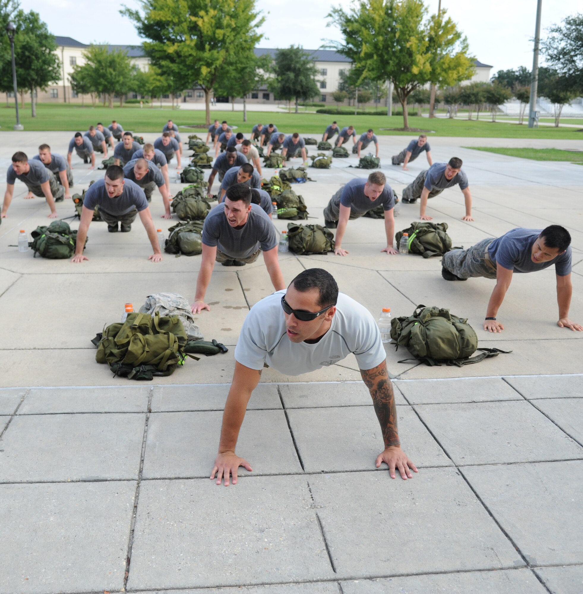 Staff Sgt. Brent Callari, 335th Training Squadron special operations weather team instructor, leads Airmen from the 334th Training Squadron combat controllers and the 335th Training Squadron special operations weather team in push-ups as they conclude a memorial physical training session Sept. 27, 2013, at Keesler Air Force Base, Miss.  The PT event was in memory of combat controller Senior Airman Mark Forester who was killed in action on Sept. 29, 2010. (U.S. Air Force photo by Kemberly Groue)
