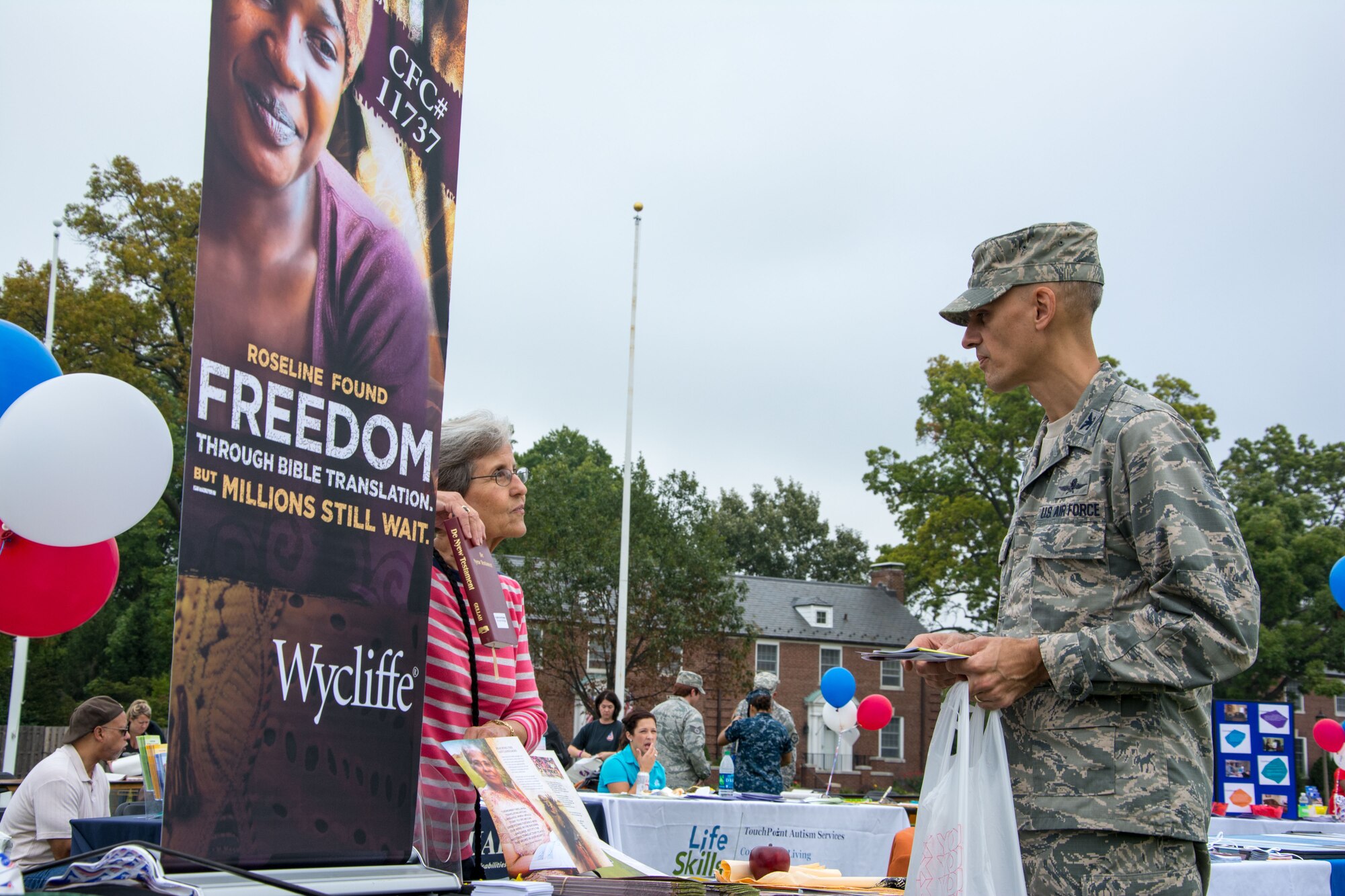 Col. Michael Cote speaks with Susan Stanes about the organization Wycliffe during the Combined Fedaral Campaign kick-off event Oct. 1, 2013, Scott AFB, Ill. Cote and other Scott AFB members were able to speak with and learn from the more than 140 volunteers representing a number of charities. Cote is the 375th Communications Group commander. (U.S. Air Force photo/Staff Sgt. Jonathan Fowler)