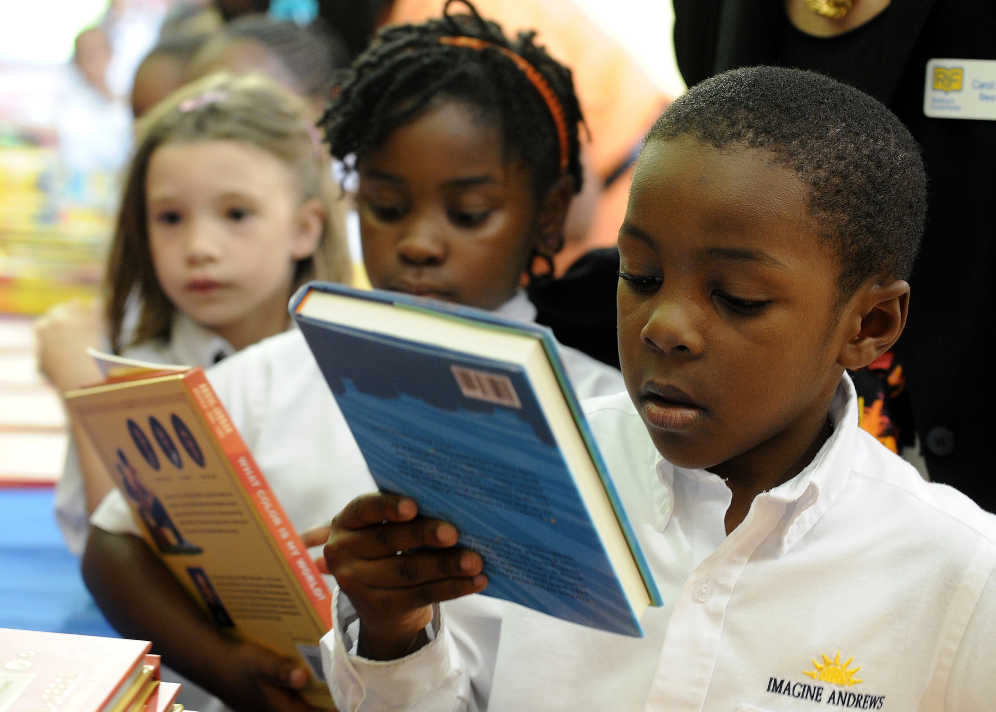 Children receive books during a Reading is Fundamental event at the Youth Center on Joint Base Andrews, Md., Oct. 1, 2013. Kareem Abdul-Jabbar attended the event hosted by Joint Base Andrews and the RIF organization to help encourage and motivate children to become life-long readers. Jabbar, author and the current leading scorer in the National Basketball Association's history, read to the children. Afterword, each child went home with books by Jabbar along with other books and prizes. (U.S. Air Force photo/ Staff Sgt. Nichelle Anderson)