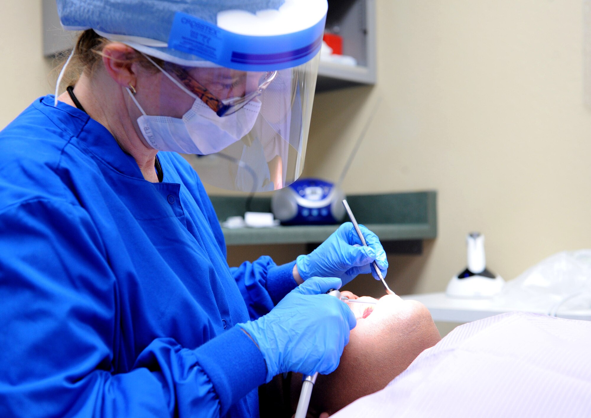 Helene Bickerdike, 7th Aerospace Medical Squadron dental hygienist, operates on Tech. Sgt. Marc Larion, 7th Maintenance Group, Sept. 26, 2013, at the 7th Medical Group on Dyess Air Force Base, Texas. Active duty members must get a dental exam yearly. (U.S. Air Force photo by Airman 1st Class Kedesha Pennant/Released)