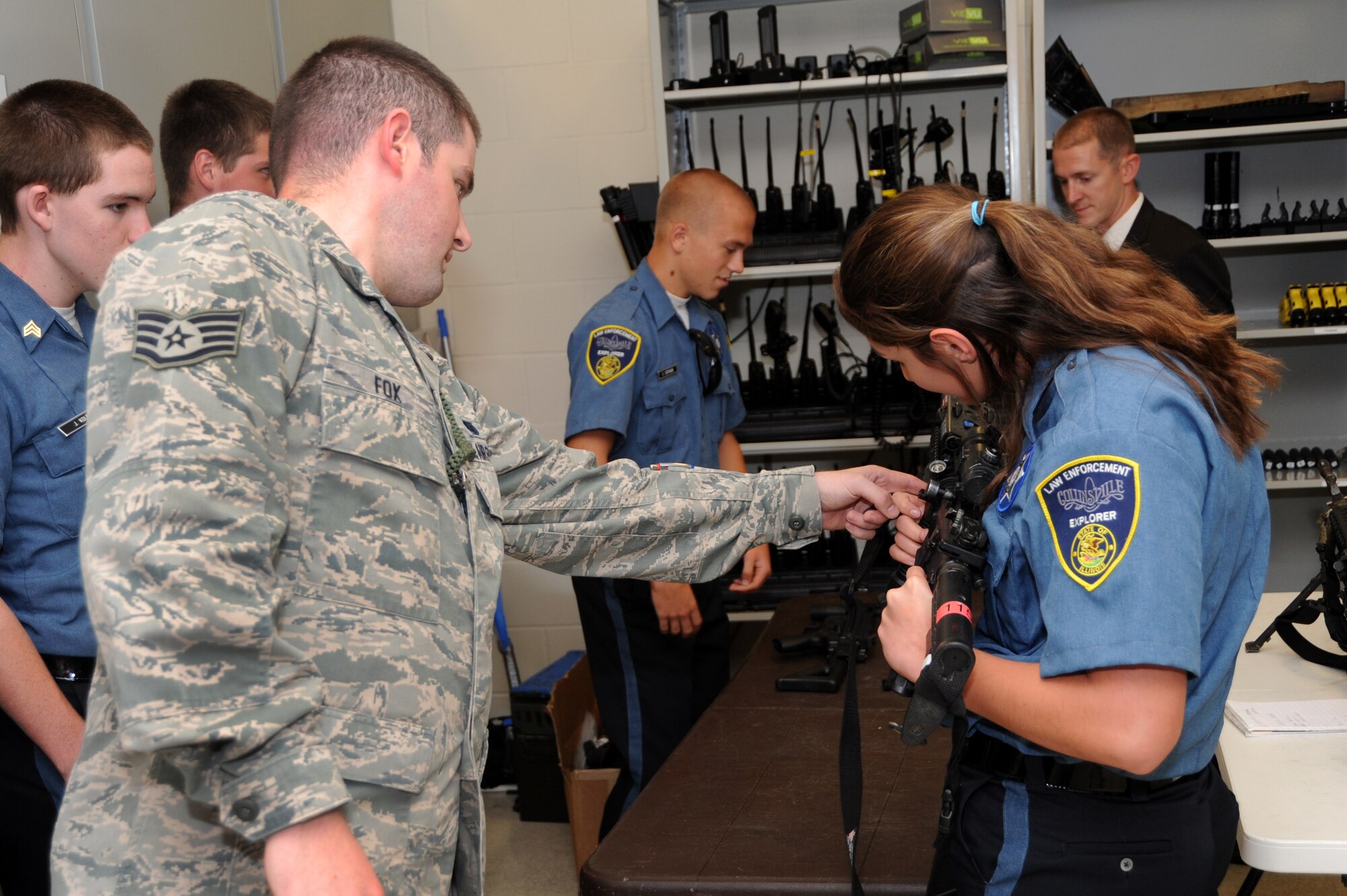 Staff Sgt. Derek Fox, 375th Security Forces NCOIC of Armory shows an explorer, Amber Fitzgerald the parts of the weapon while other explorers look at different weapons with Office of Special Investigations special agent, James Hoy at the Security Forces Armory Sept. 25, 2013. Hoy was part of the explorers program in his hometown for four years when he was younger. (U.S. Air Force photo/Airman Megan Friedl)