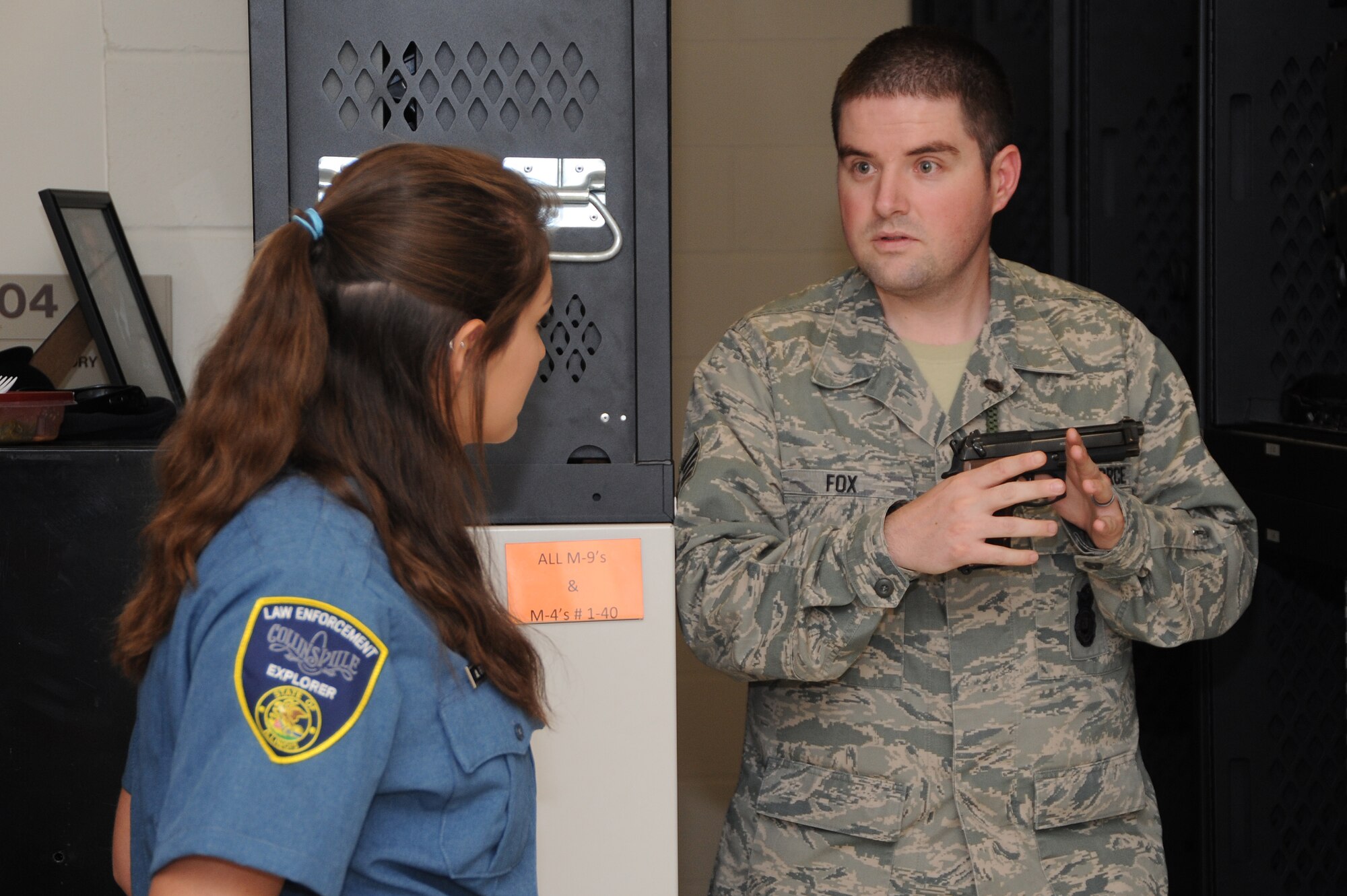 Staff Sgt. Derek Fox, 375th Security Forces NCOIC of Armory holds an M-9 while telling an explorer, Amber Fitzgerald about the weapon at the Security Forces Armory Sept. 25, 2013. The weapons in the armory are under high surveillance and always need to be checked in and out properly. (U.S. Air Force photo/Airman Megan Friedl)