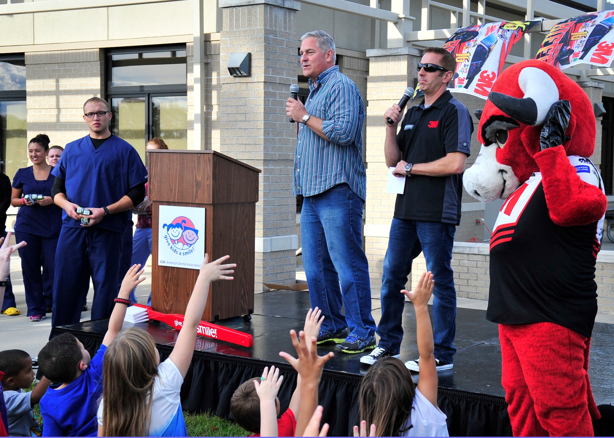 Greg Biffle (right center), driver of the No. 16 3M Ford, and John Roberts, Speed Channel announcer, interact with kids and promote dental health Sept. 26, 2013, at the youth center on Dover Air Force Base, Del. Biffle was at Dover to promote the Give Kids a Smile campaign, which promotes dental health and awareness for children. (U.S. Air Force photo/Tech. Sgt. Chuck Walker)