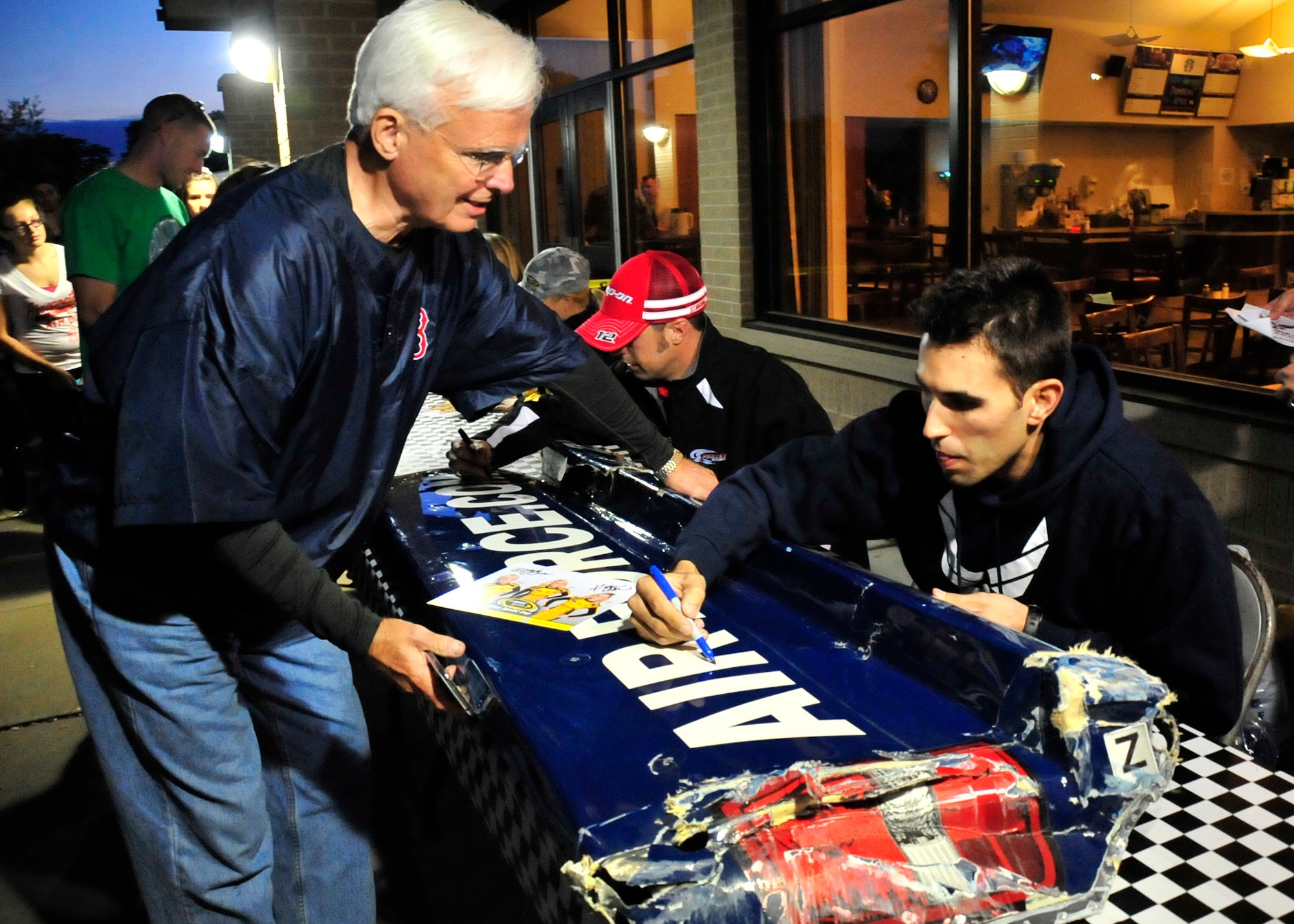 Aric Almirola, driver of the No. 43 U.S. Air Force Ford, autographs a bumper off of his car for a race fan at the Race Weekend Social Sept. 27, 2013, at Mulligan’s on Dover Air Force Base, Del. Almirola was on base to interact with race fans, sign autographs and to take pictures with fans. (U.S. Air Force photo/Tech. Sgt. Chuck Walker)