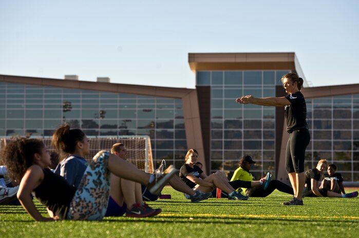 Missy Cornish, wife of Col. Barry Cornish, 99th Air Base Wing commander, leads a warrior trained fitness workout on the field at the track behind the Warrior Fitness Center Sept. 26, 2013, at Nellis Air Force Base, Nev.  The Warrior trained fitness event was designed with five exercise stations consisting of cardio and strength training workouts. (U.S. Air Force photo by Airman 1st Class Christopher Tam)