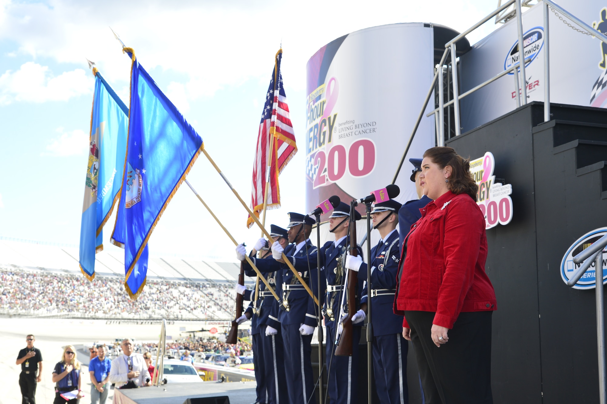 Kristin Moore, wife of Col. Rick Moore, 436th Airlift Wing commander, sings the National Anthem while the Dover Air Force Base Honor Guard presents the colors before the start of the 5-Hour Energy 200 benefiting Living Beyond Breast Cancer Sept. 28, 2013, at Dover International Speedway in Dover, Del. Moore, who is an opera singer, sang the anthem as part of the pre-race ceremonies. (U.S. Air Force photo/David Tucker)