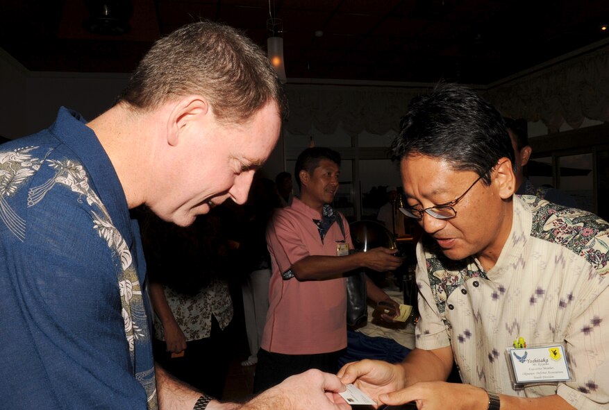 U.S. Air Force Brig. Gen. James Hecker, 18th Wing commander, and Yoshitaka Koyama, Okinawa Defense Association Youth Division vice president, exchange “meishi” (business cards) during an Honorary Commanders social event at the Kadena Marina seaside restaurant, Okinawa, Japan, Oct. 1, 2013. The purpose of exchanging meishi in Japan is to provide names and contact information at the beginning of a conversation.  (U.S. Air Force photo by Naoto Anazawa)