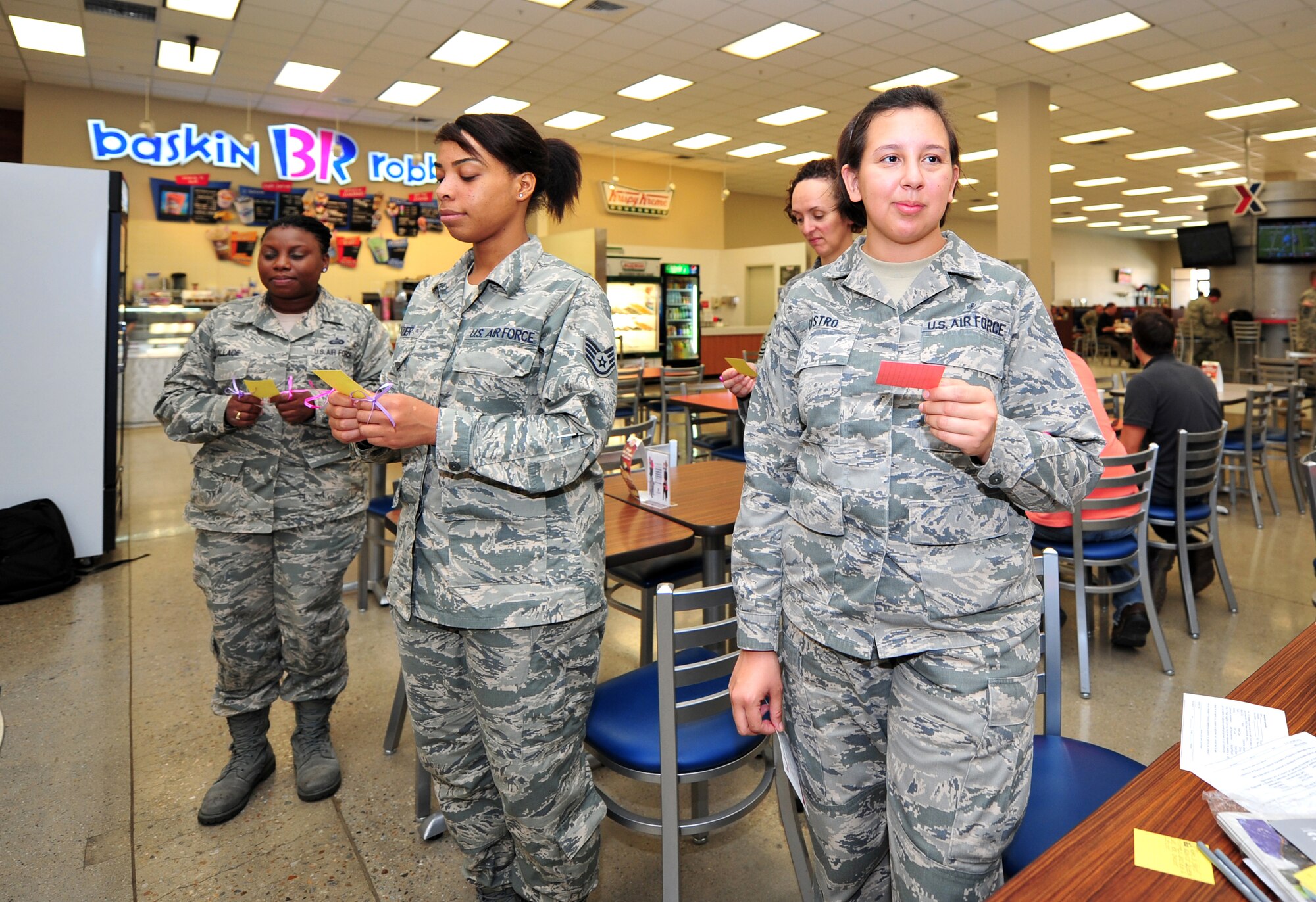 Airmen stand in silence while holding cards showing statistics about breast cancer and domestic violence during a Breast Cancer and Domestic Violence Awareness Month flash mob at Osan Air Base, Republic of Korea, Oct. 1, 2013. Approximately 25 people took a stand in the base Exchange food court to show their support for finding a cure for breast cancer and to encourage sufferers of domestic violence to speak out. (U.S. Air Force photo/Airman 1st Class Ashley J. Thum)