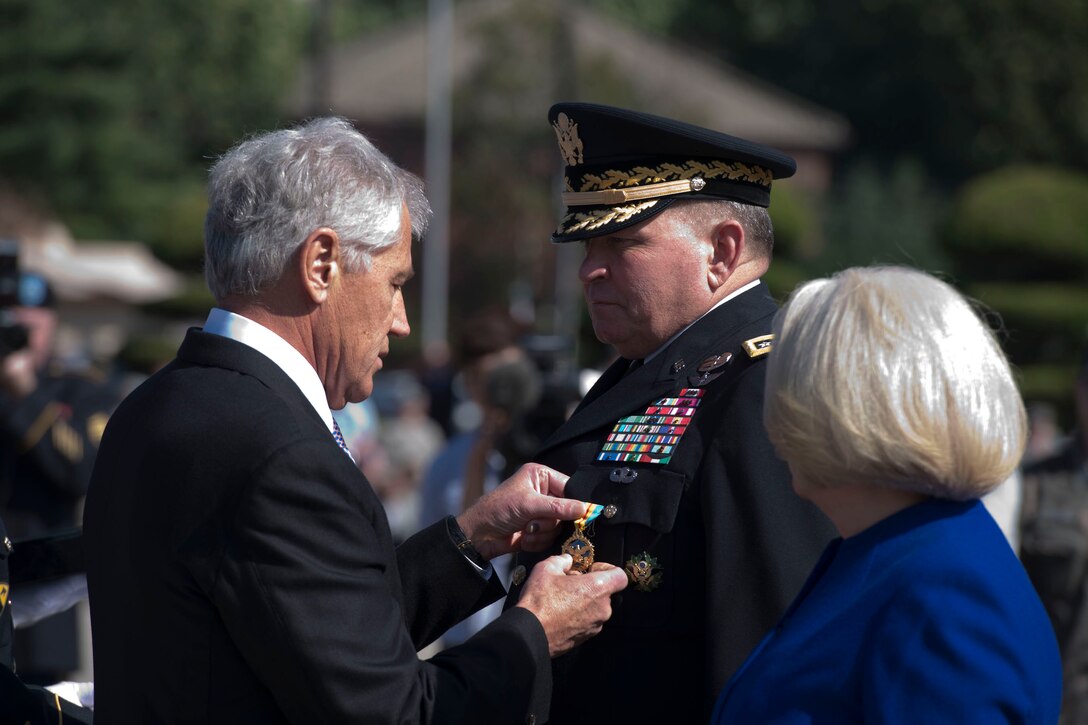 U.S. Defense Secretary Chuck Hagel presents U.S. Army Gen. James D. Thurman, outgoing commanding general of U.S. Forces Korea, with an end-of-tour award as Thurman's wife, Dee Thurman, looks on during a change-of-command ceremony in Seoul, South Korea, Oct. 2, 2013.