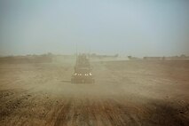 A Mine Resistant, Ambush Protected vehicle passes through a gust of sand during a convoy conducted by Combat Logistics Regiment 2, Regional Command (Southwest), in Helmand province, Afghanistan, Sept. 15, 2013. The challenging conditions of desert driving test the skills of drivers and vehicle commanders alike during resupply operations throughout the region.