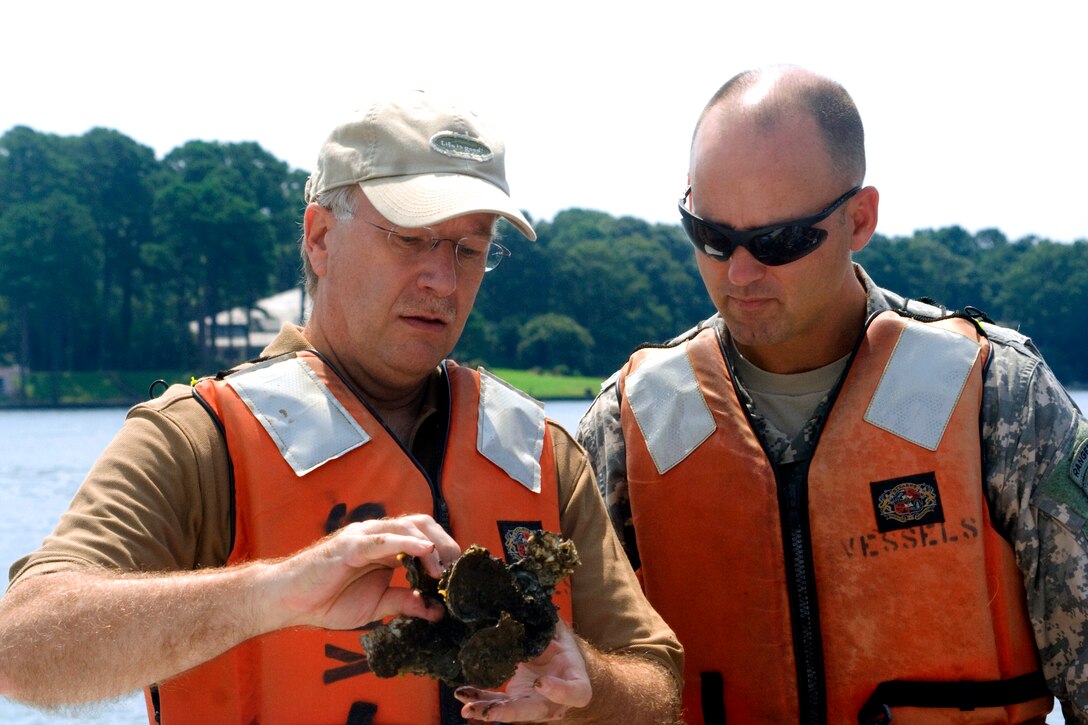 VIRGINIA BEACH, Va -- Colonel Andrew Backus (right), commander of the Norfolk District, U.S. Army Corps and Engineers, and Jack Travelstead, deputy of the Virginia Marine Resource Commission, examine oysters from the Lynnhaven.