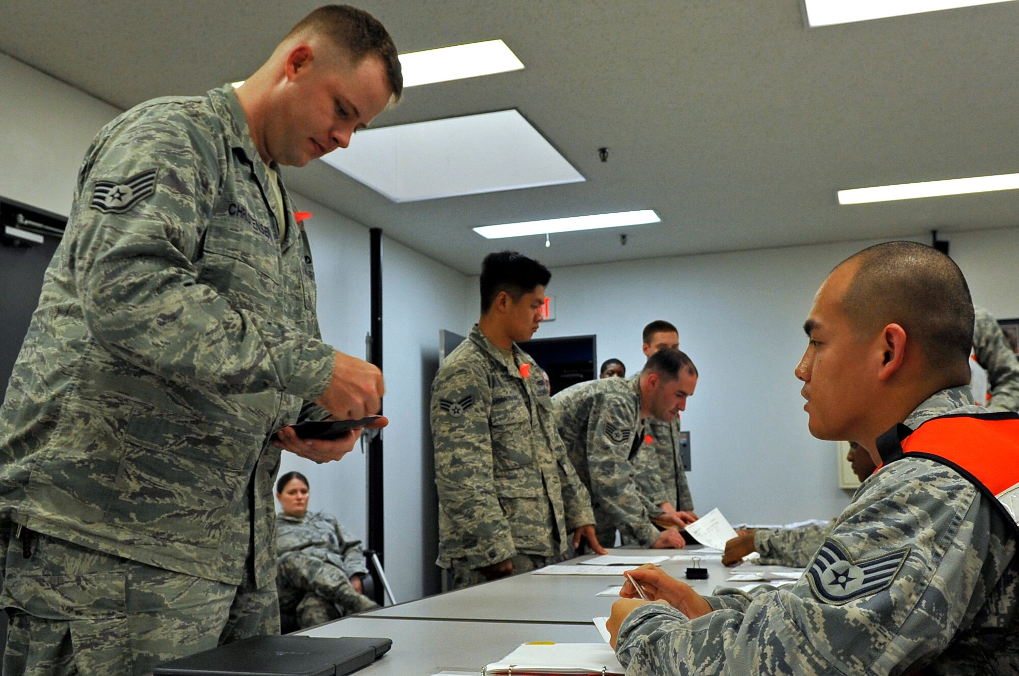 U.S. Air Force Staff Sgt. Joshua Christensen, left, 35th Civil Engineer Squadron exercise augmentee, processes the personnel deployment function line during an Operational Readiness Exercise at Misawa Air Base, Japan, Oct. 2, 2013. The purpose of the PDF line is to ensure Airmen have all of their personnel, legal, medical and financial actions squared away prior to supporting combat operations. (U.S. Air Force photo by Airman 1st Class Zachary Kee)