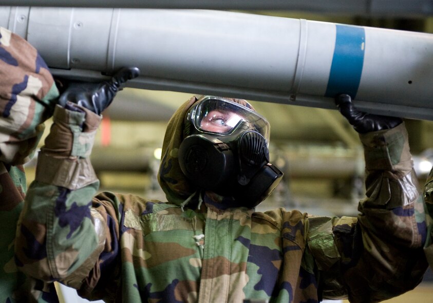 Senior Airman Katie McFerran, 8th Aircraft Maintenance Squadron load crew member, lifts a missile into place at Kunsan Air Base, Republic of Korea, Oct. 2, 2013. McFerran, along with other load crew members from the 8th AMXS, practiced loading weapons on F-16 Fighting Falcons in full mission oriented protective posture gear during exercise Beverly Midnight 13-4. (U.S. Air Force photo by Senior Airman Armando A. Schwier-Morales/ Released)
