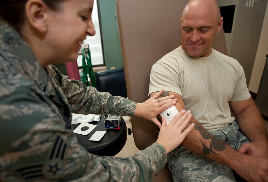 Senior Airman Haylley Turney, 28th Medical Operations Squadron physical therapy technician, applies a medicated electro pad on Master Sgt. Andrew Bousley, 28th Munitions Squadron line delivery section chief, during an appointment at Ellsworth Air Force Base, S.D., Oct. 2, 2013. Physical medicine specialists help Airmen perform exercises designed to help them recover from muscle and bone injuries. (U.S. Air Force photo by Airman 1st Class Alystria Maurer/Released)