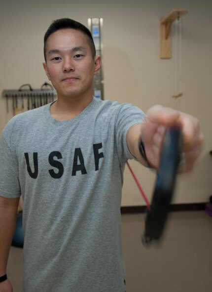 Capt. Chad Nishizuka, 34th Bomb Squadron chief of weapons and tactics, uses a resistance band to strengthen his rotator cuff during a physical therapy appointment at Ellsworth Air Force Base, S.D., Oct. 2, 2013. The 28th MDOS physical therapy clinic is a rehabilitative health treatment center that utilizes exercises and other therapeutic methods as a way of helping individuals regain or improve their physical abilities. (U.S. Air Force photo by Airman 1st Class Alystria Maurer/Released)