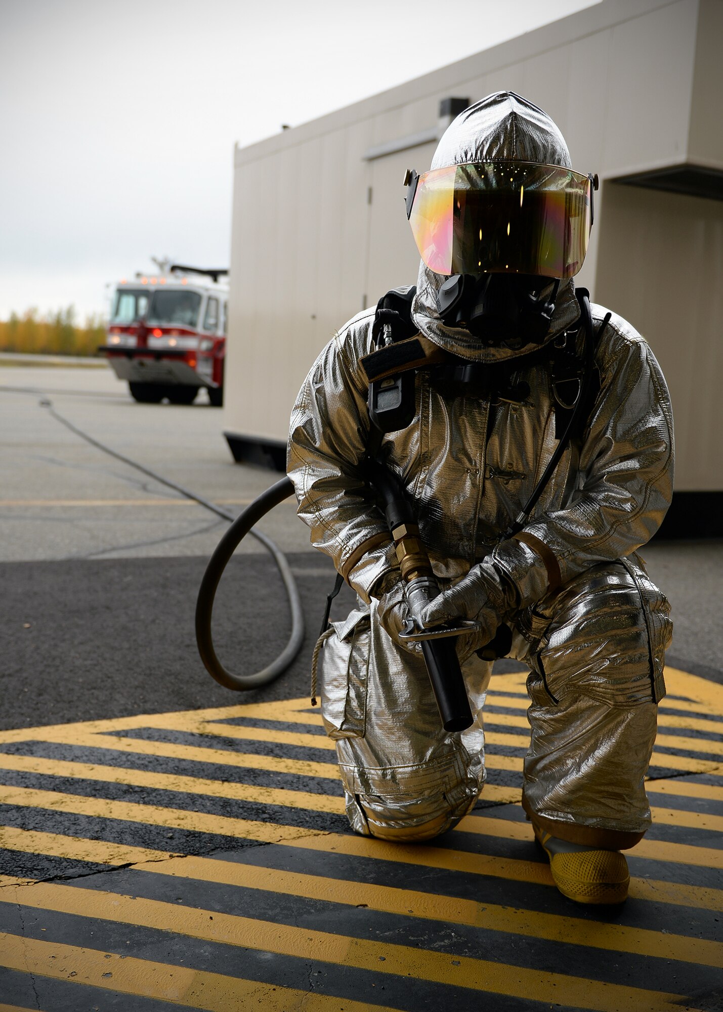 Staff Sgt. Jerry Hann, 354th Civil Engineer Squadron lead firefighter, kneels ready to respond with fire retardant in case of an aircraft fire while training with a simulated unconscious pilot in an aircraft Sept. 19, 2013, Eielson Air Force Base, Alaska. Emergency responders train for a variety of situations throughout their shifts to maintain readiness. (U.S. Air Force photo by Senior Airman Shawn Nickel/Released)