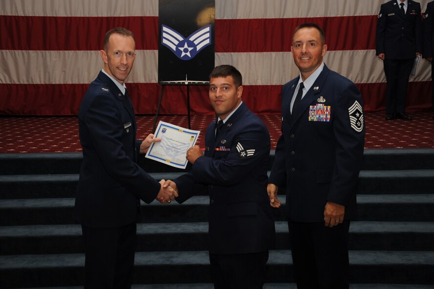 Senior Airman Nick Nikopoulos, 2nd Maintenance Squadron, receives a certificate of promotion from Col. Leland Bohannon, 2nd Bomb Wing vice commander, and Chief Master Sgt. Curtis Storms, 2nd Bomb Wing command chief, during the September Wing Promotion Ceremony on Barksdale Air Force Base, La., Sept. 30, 2013. (U.S. Air Force photo/Senior Airman Sean Martin)