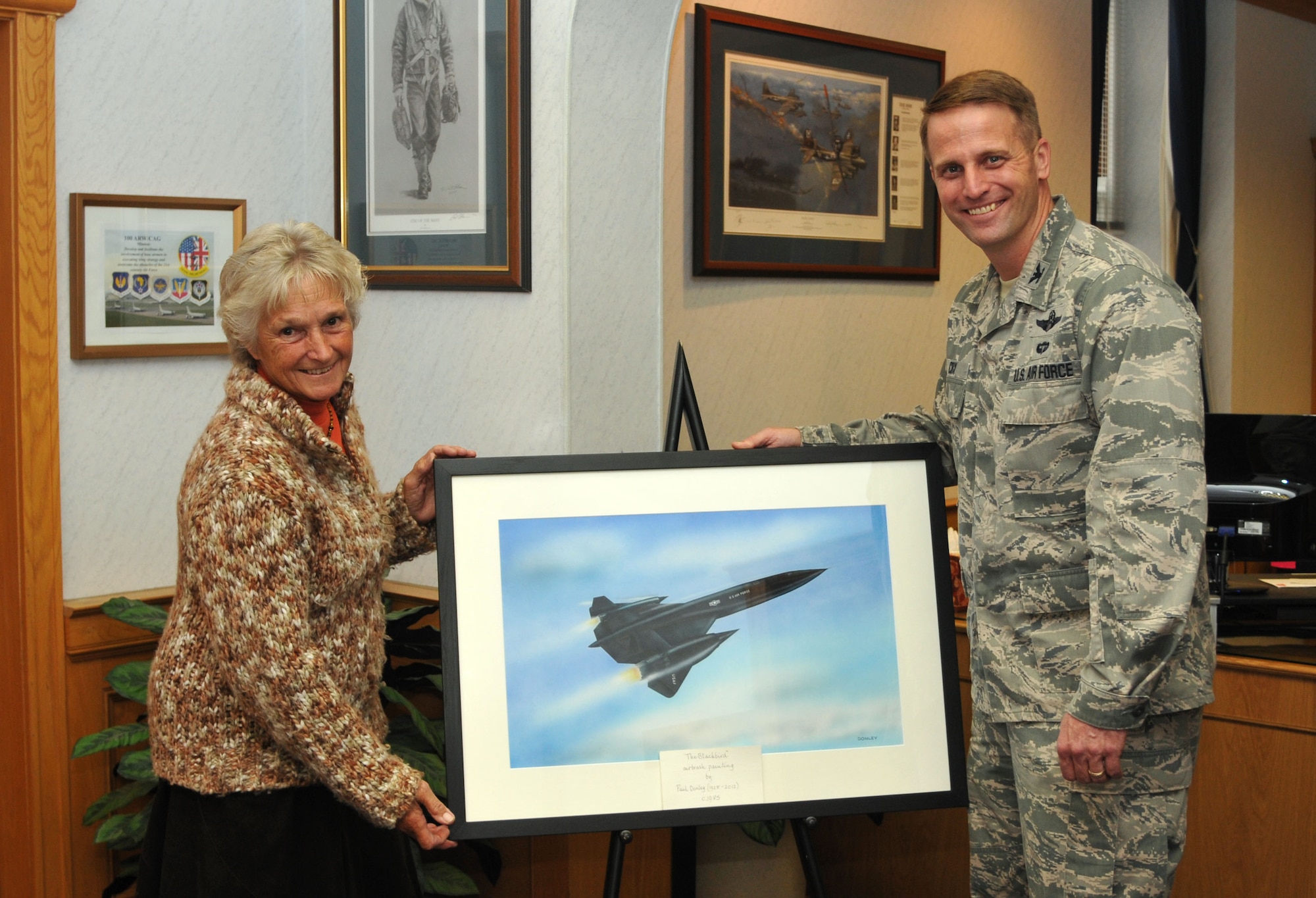 U.S. Air Force Col. David Cox, right, 100th Air Refueling Wing vice commander, receives a painting of an SR-71B Blackbird Oct. 2, 2013, in the wing headquarters building on RAF Mildenhall, England. Jill Donley presented the painting to the base on behalf of her late husband, Paul, who painted the picture in 1985. (U.S. Air Force photo by Airman 1st Class Kelsey Waters/Released)