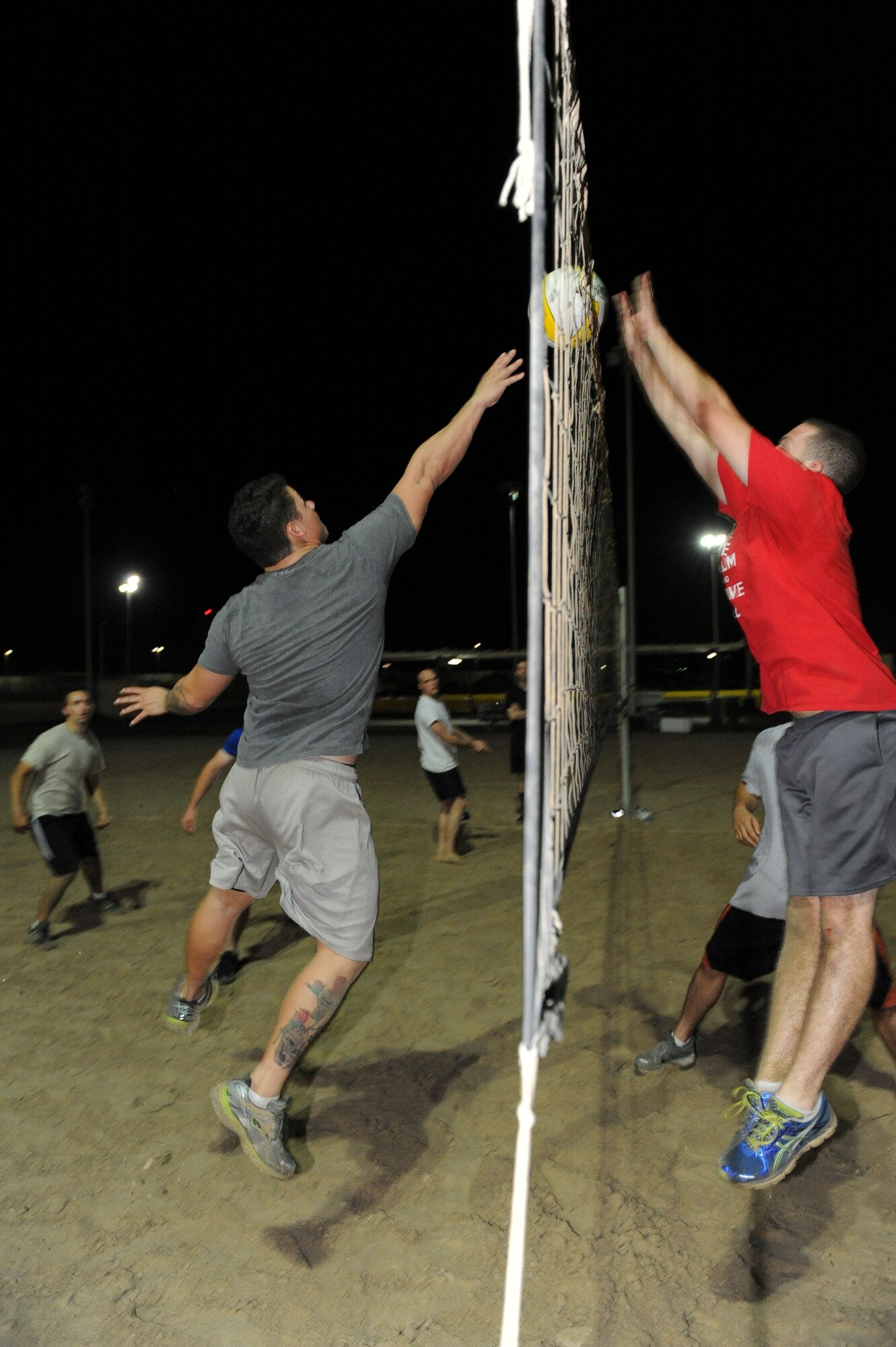 Robert English, left, Force Protection 1 volleyball player, tries to tip a ball past Adam Powers, CEX/CEF v-ball player, during the championship game at an undisclosed location in Southwest Asia Sept. 30, 2013.  The CEX/CEF v-ball team was able to edge out their competition to win the game in two sets. English is deployed from Altus Air Force Base, Okla. Powers is deployed from Joint Base Pearl Harbor-Hickam, Hawaii. (U.S. Air Force photo by Staff Sgt. Joshua J. Garcia)