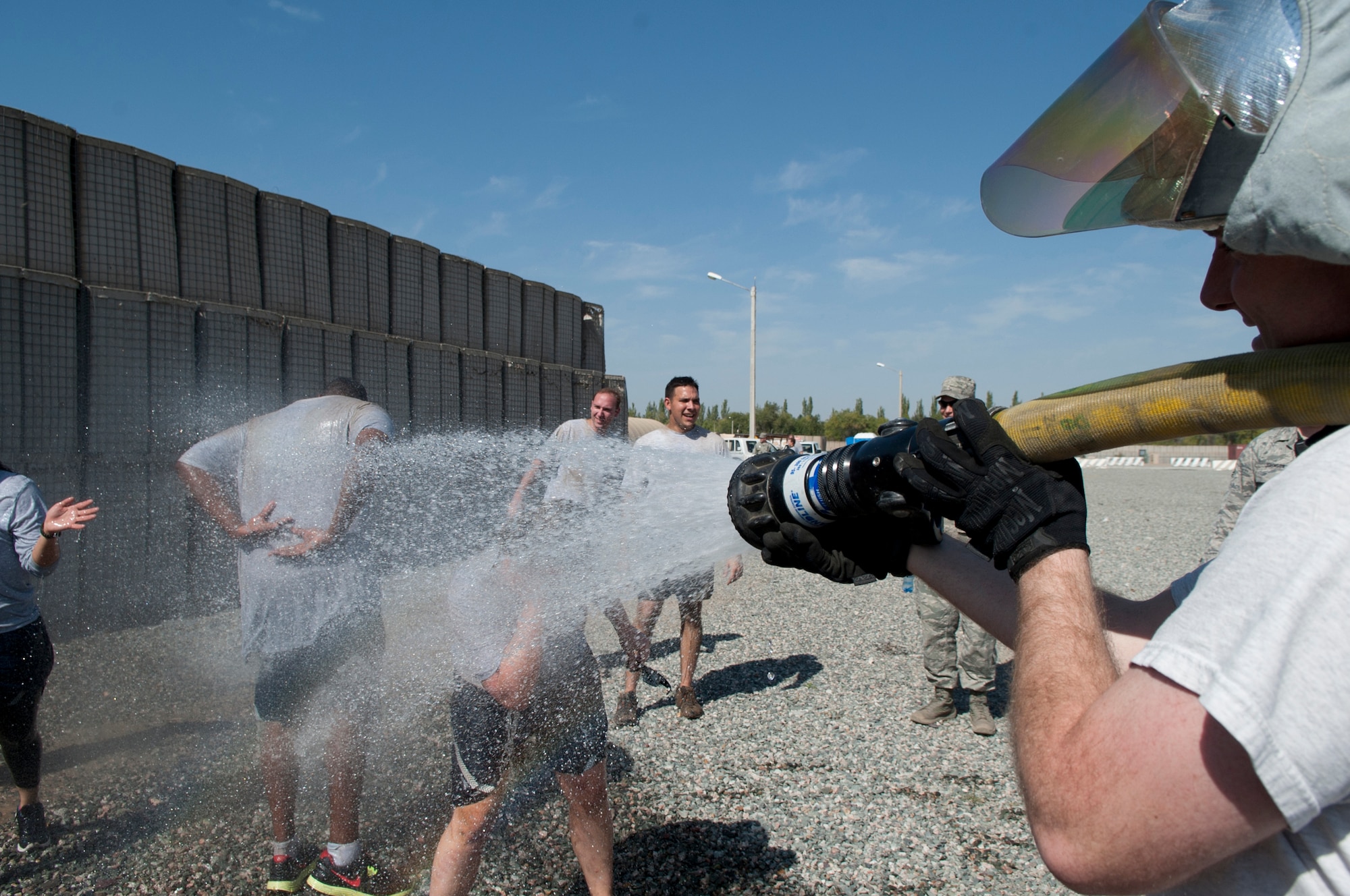 Service members who participated in the "Filthy 5K" are hosed down, courtesy of the 376th Expeditionary Civil Engineer Squadron fire department, at Transit Center at Manas, Kyrgyzstan, Sept. 29, 2013. The funds raised during the event were used to support the Transit Center Combined Federal Campaign goal of $50,000. (U.S. Air Force/Staff Sgt. Robert Barnett)