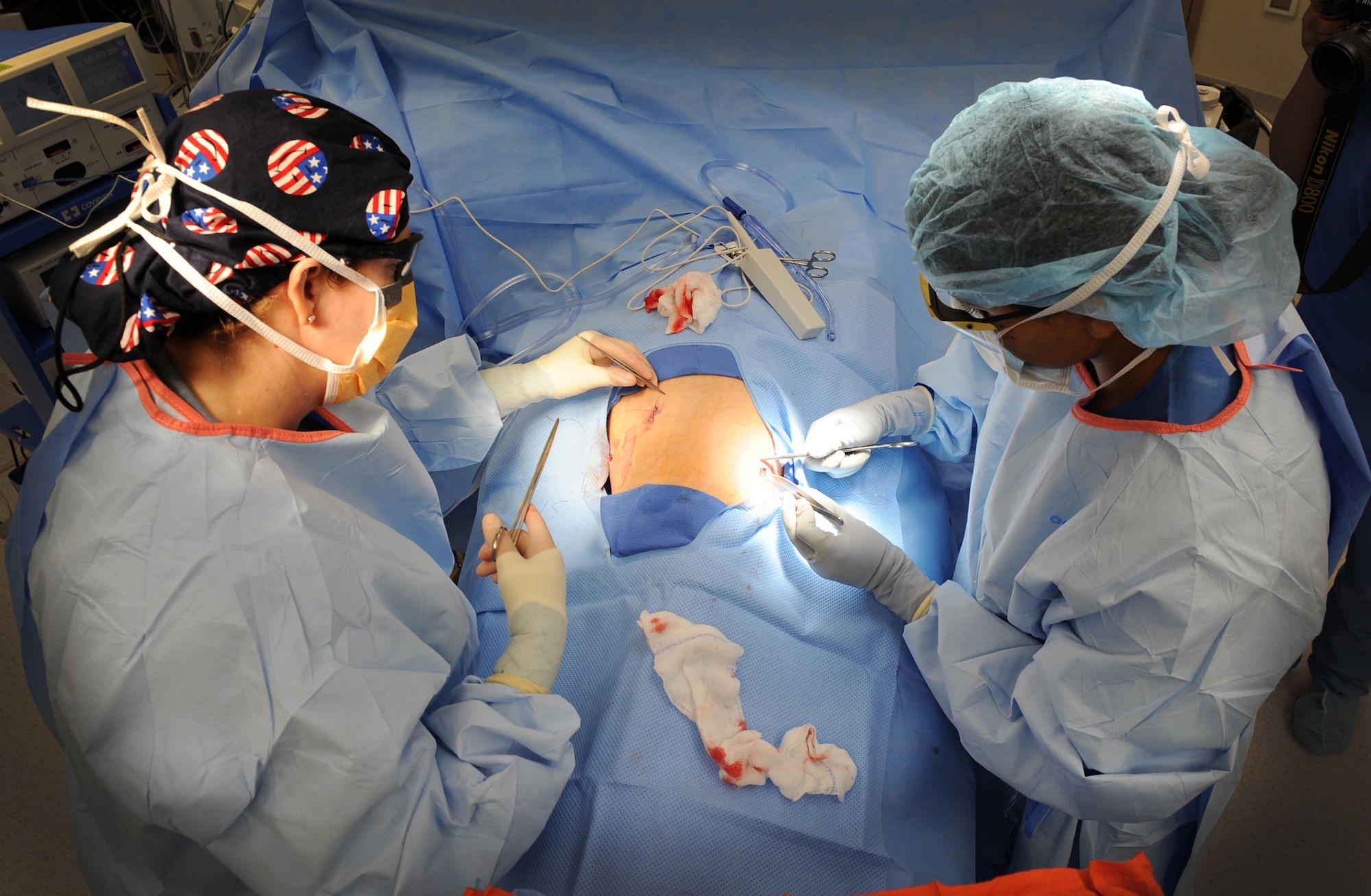 (From left) Lt. Col. (Dr.) Sandra Early and Airman 1st Class Sylvia Zamora close and dress incisions, Sept. 25, 2013, at Aviano Air Base, Italy. To anticipate what tool a surgeon will need next, a surgical technician must be as familiar with the procedure as the surgeon. Early is the surgical services medical director and Zamora is a surgical technician, both part of the 31st Surgical Operations Squadron. (U.S. Air Force photo/Airman 1st Class Matthew Lotz)