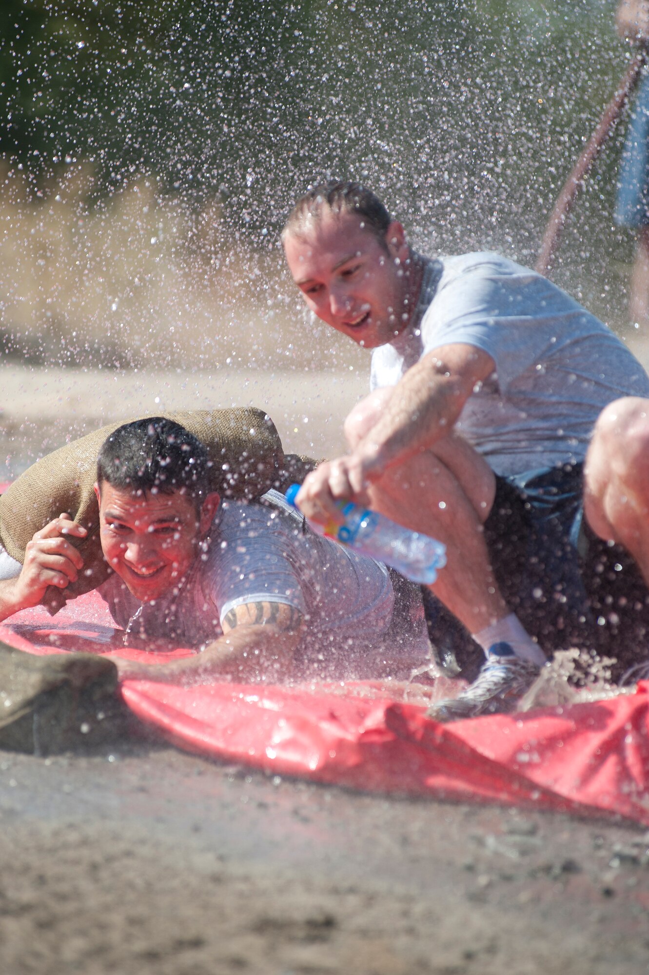 Senior Airman Matthew Hanning, left, and Tech. Sgt. Scott Clements slide through water during the "Filthy 5K" event at Transit Center at Manas, Kyrgyzstan, Sept. 29, 2013. Hanning and Clements are members of the 376th Expeditionary Logistics Readiness Squadron and are deployed out of Homestead Air Reserve Base, Fl. (U.S. Air Force photo/Staff Sgt. Robert Barnett)