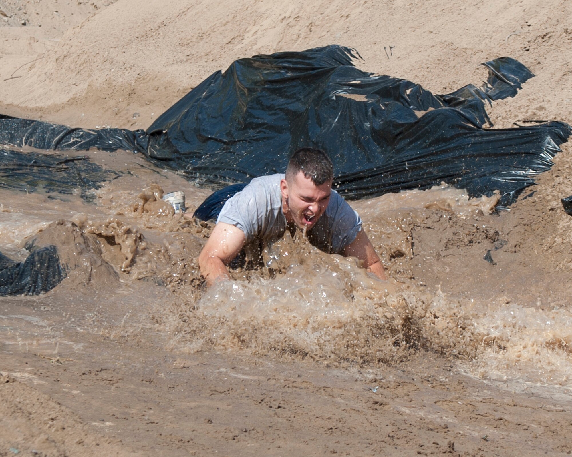 An Air Force member dives through a mud pit during the "Filthy 5K" event in Frunzy Forest at Transit Center at Manas, Kyrgyzstan, Sept. 29, 2013. The recreational event raised $735 for the United Healthcare Children's Foundation, a charity supported by the Combined Federal Campaign. (U.S. Air Force photo/Staff Sgt. Robert Barnett)