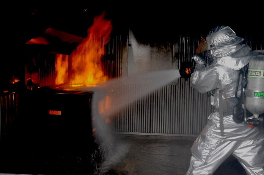 An Airman from the 8th Civil Engineer Squadron fire department extinguishes a fire during a structural fire training scenario at Kunsan Air Base, Republic of Korea, Oct. 1, 2013. This training was part of exercise Beverly Midnight 13-4 and ensures the fire dogs are always ready for any situation. (U.S. Air Force photo by Staff Sgt. Jessica Haas/Released)