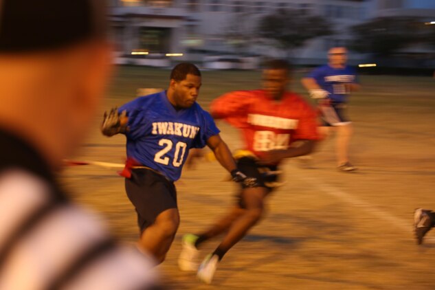 Hospital Man Petty Officer 3rd class Corey Holmes,11 th Dental company dental technician (Blue) runs with the ball while simultaneously getting his flag pulled during an intramural flag football game behind the Robert M. Casey Medical and Dental Clinic aboard Marine Corps Air Station Iwakuni, Japan, Oct. 3, 2013. 