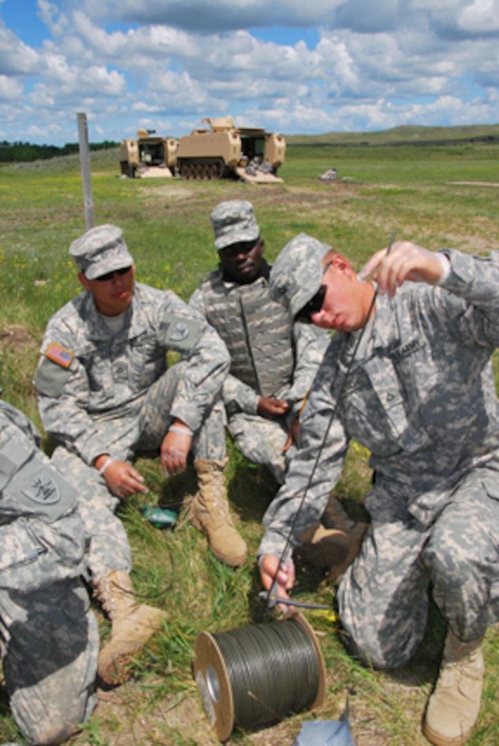 Pfc. Javier Ortiz, West Fargo, N.D., and 1st Lt. Frank Amponsah, Ghana army, watch Spc. Cody Lausch, Hannaford, N.D., cut a piece of detonation cord on the demolition range at Camp Grafton South, south of Devils Lake, N.D., June 21. The North Dakota Army National Guard's 817th Engineer Company (Sapper), Jamestown, are working with their Ghanaian partners in an exchange visit during annual training. The Sappers are using crater charges and other explosives. North Dakota and Ghana are linked through the Department of Defense-sponsored State Partnership Program.