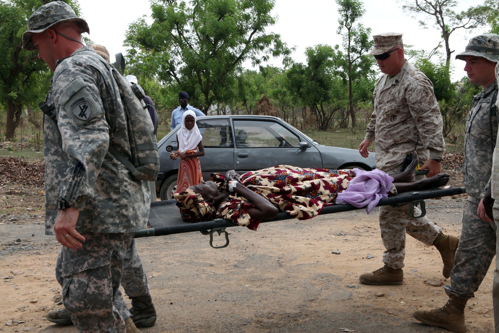 U.S. service members carry a local woman unable to walk into the gates of the clinic in Thies, Senegal, July 11, 2012. The medical care provided by U.S. service members is part of Exercise Western Accord 2012, a multi-lateral exercise with Senegalese and several West Africa nations. The training exercise runs from June 26 - July 24 and involves the armed forces of Senegal, Burkina Faso, Guinea, Gambia and France, as well as U.S. service members – primarily Reservists from the Marines, Army, Navy, and Air Force.