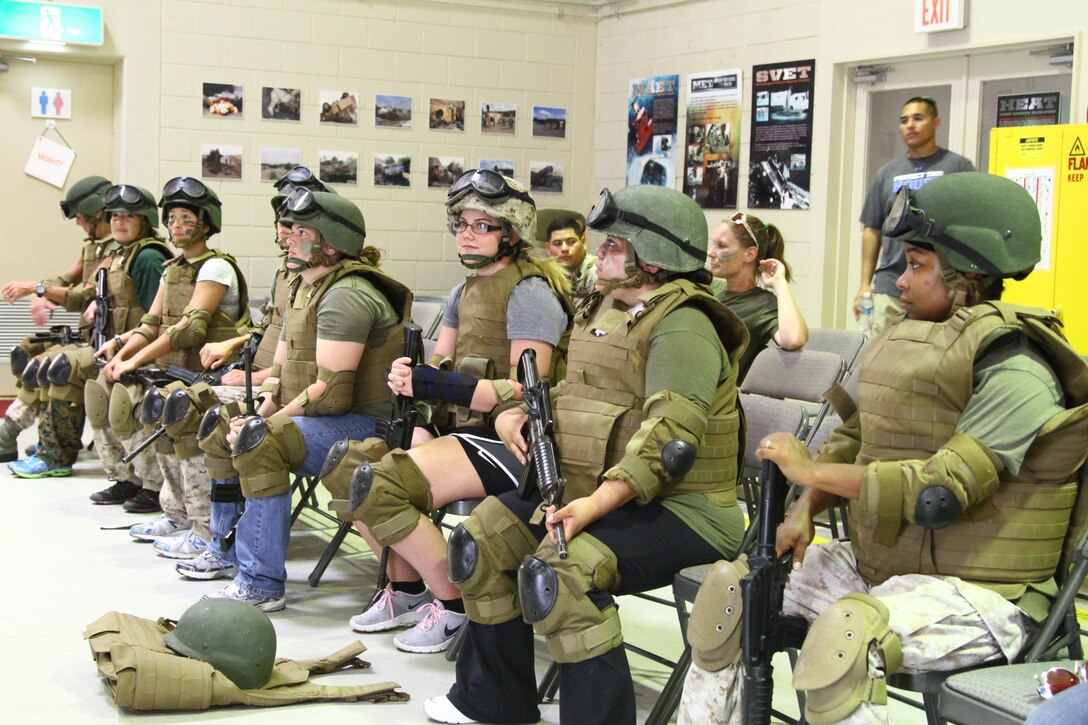 A group of military spouses don protective gear before receiving a Humvee egress assistance trainer safety briefing Sept. 27 on Camp Hansen. The HEAT experience exposed spouses to some of the training their service members go through during the Spouses Warrior Day hosted by family readiness officers from across the 3rd Marine Logistics Group. The significant others to these spouses are part of various units in the 3rd MLG, III Marine Expeditionary Force. 