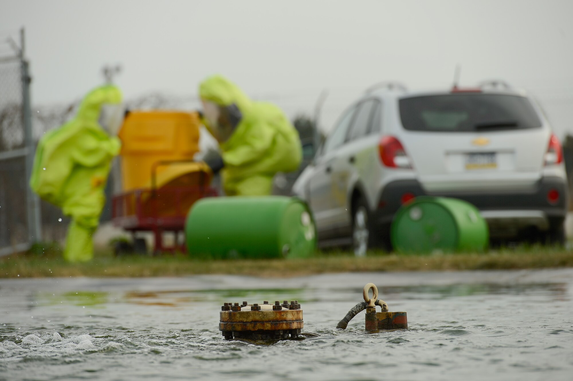 A pump is partially submerged and non-functioanl in the scenario provided to Staff Sgt. Jaimee Scott (left), 436th Aeromedical Squadron and Technical Sgt. Justin Alexander, 436th Civil Engineer Squadron, (wearing bright green hazardous material protection suits) as they  who work to contain a simulated chemical spill at Dover Air Force Base, Del. on Oct. 3, 2013. The airmen are participating in a joint unit training exercise between the 436th Medical Group and 436th Civil Engineer Squadron which tests the bases ability to respond to a natural disaster and resulting contamination to water supplies. (U.S. Air Force photo/Greg L. Davis)