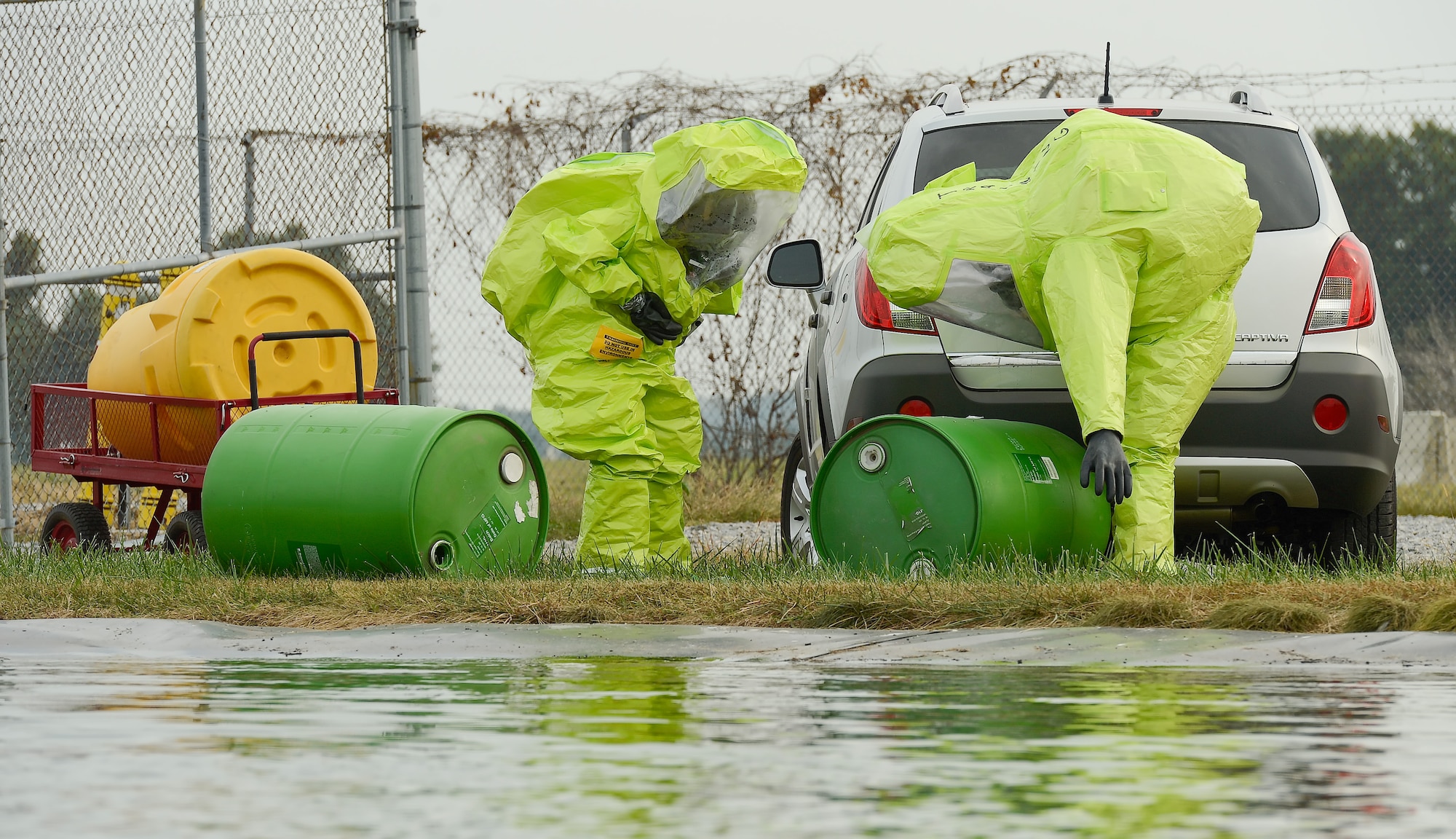 Staff Sgt. Jaimee Scott (left), 436th Aeromedical Squadron and Technical Sgt. Justin Alexander, 436th Civil Engineer Squadron wear bright green hazardous material protection suits as they approach a staged scene simulating a chemical spill with potential water contamination at Dover Air Force Base, Del. on Oct. 3, 2013. The airmen are participating in a joint unit training exercise between the 436th Medical Group and 436th Civil Engineer Squadron which tests the bases ability to respond to a natural disaster and resulting contamination to water supplies. (U.S. Air Force photo/Greg L. Davis)