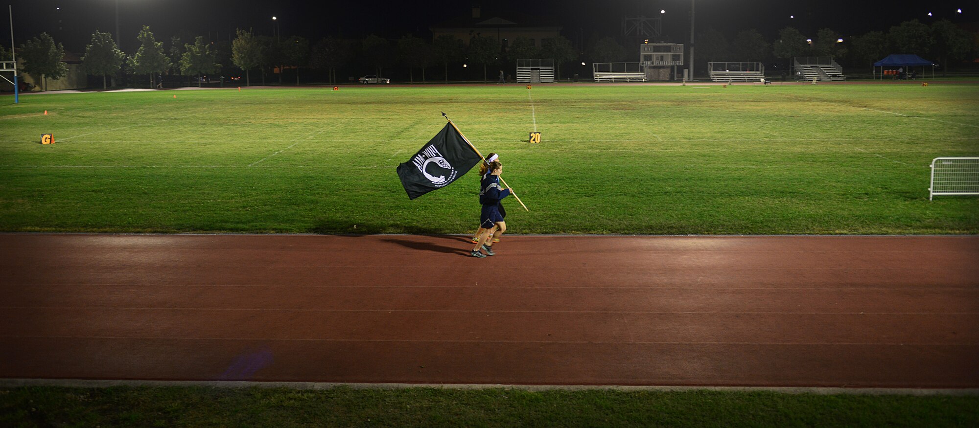 Second Lt. Samantha Beatty, 31st Fighter Wing protocol deputy chief, and Senior Airman Amber Swearengin, 31st FW command chief executive assistant, run with the Prisoners of war/Missing in action memorial flag, Oct. 2, 2013, at Aviano Air Base, Italy. From Oct. 2-3, volunteers ran approximately 150 miles as part of a 24-hour vigil run to recognize POWs and those MIA.  (U.S. Air Force photo/Staff Sgt. Evelyn Chavez) 