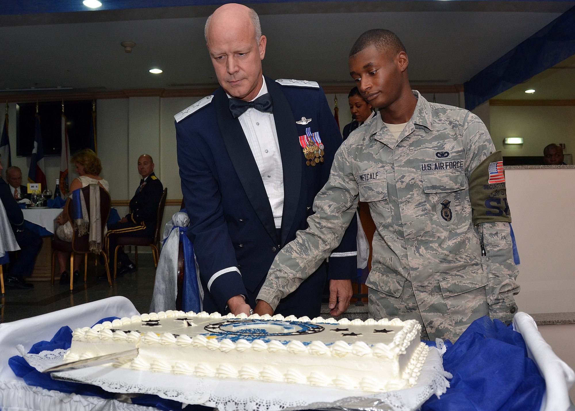 Maj. Gen Thomas P. Harwood and Airman 1st Class Julian Metcalf slice a cake during an annual Air Force Ball at the 64th Air Expeditioanry Group in Southwest Asia, Sept. 20, 2013. As Air Force tradition dictates, the junior and most senior Airmen made the first cut. Harwood is the U.S. Central Command U.S. Millitary Training Mission chief to the host nation. Metcalf is 64th Expeditioanry Security Forces Squadron member deployed from Altus Air Force Base, Okla., and a Chicago native. 

