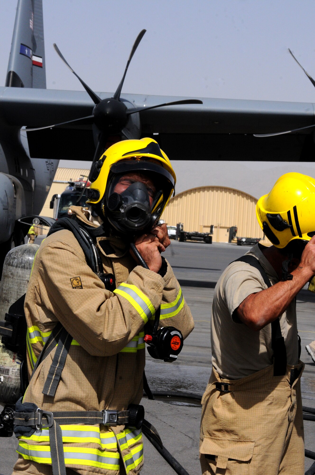 Members of the Kandahar Fire Department emergency fire response team remove their protective equipment after a training exercise where they simulated responding to a fire onboard a C-130J Hercules Sept. 28, 2013, at Kandahar Airfield, Afghanistan.  Awareness and training exercises ensure emergency responders are prepared for any situation that could arise. (U.S. Air Force photo by Senior Airman Jack Sanders)