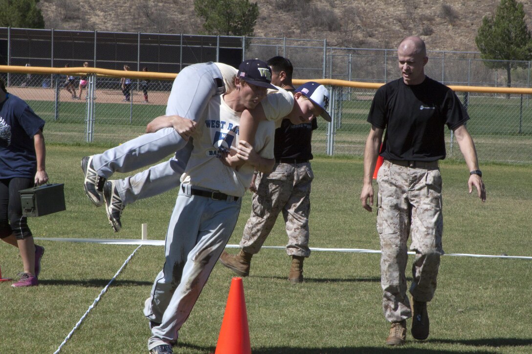 A baseball player fireman carries a teammate during the maneuver under fire portion of the combat fitness test on their baseball field in Santa Clarita, Calif., Oct. 1. Recruiting Station Los Angeles set up a CFT for the baseball and softball players at the high school.  The players learned about teamwork and leadership.