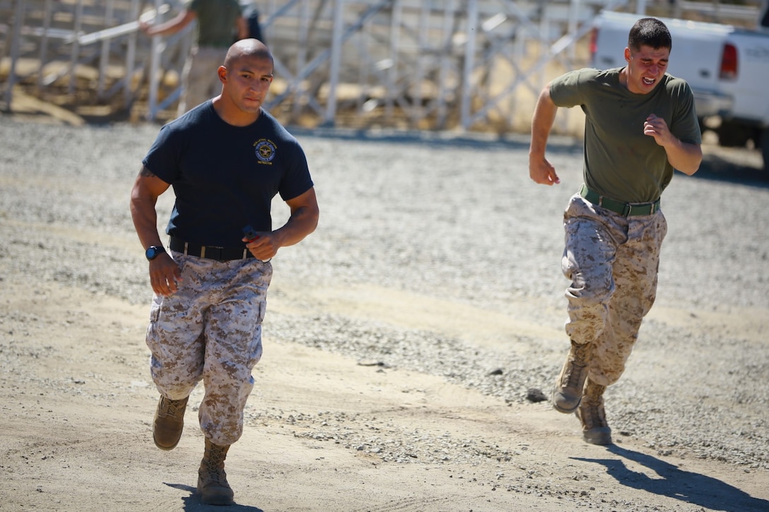 Corporal Dylan Hudson (right), fire team leader, Delta Company, 1st Battalion, 1st Marine Regiment, endures a nonlethal weapons training course where he was sprayed with pepper spray and fought off notional aggressors played by fellow Marines holding punching bags here, Oct. 1, 2013. Staff Sgt. Hector Sanchez (left), nonlethal weapons instructor, 1st Law Enforcement Battalion, guided the Marines through the course. The Marines of Delta Company are preparing for a deployment to the Middle East where they’ll provide embassy security. Hudson is a native of Seaford, Del., and Sanchez is a Chicago native.